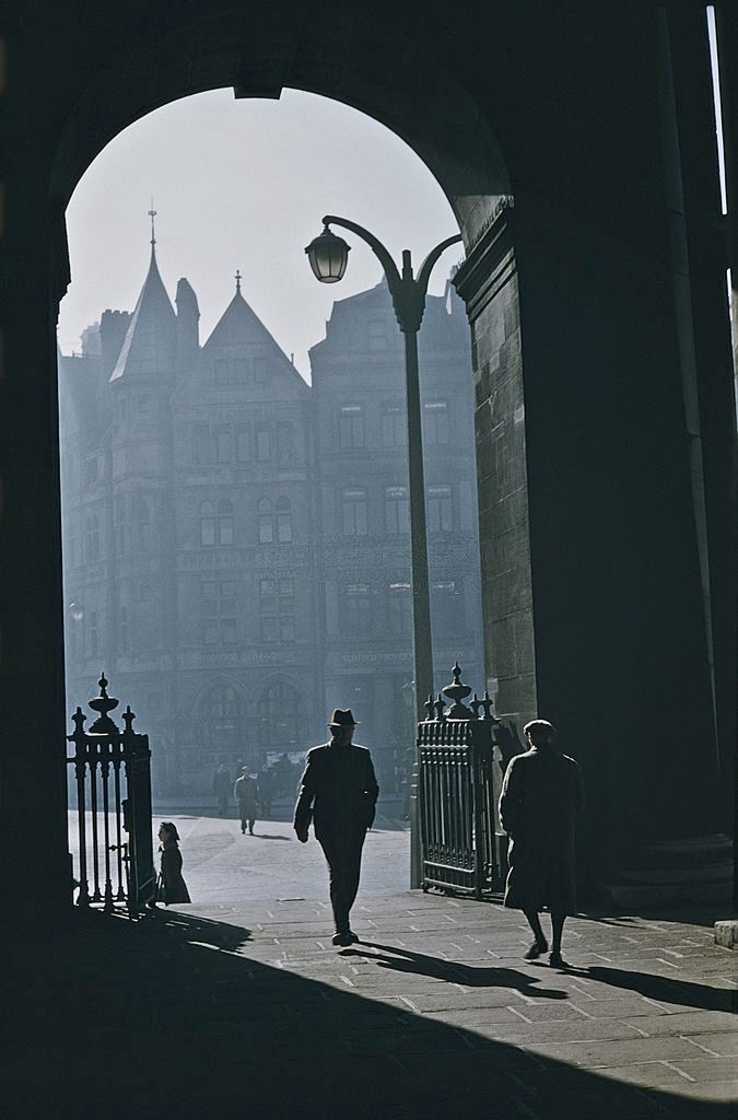 Pedestrians walking through an arched gateway in Belfast, 1955.