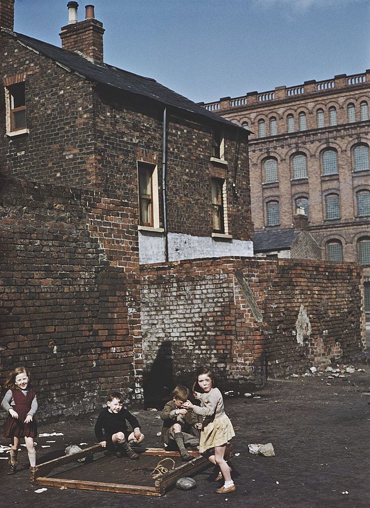 A group of children playing with an old bed frame on waste ground in Belfast, 1955.