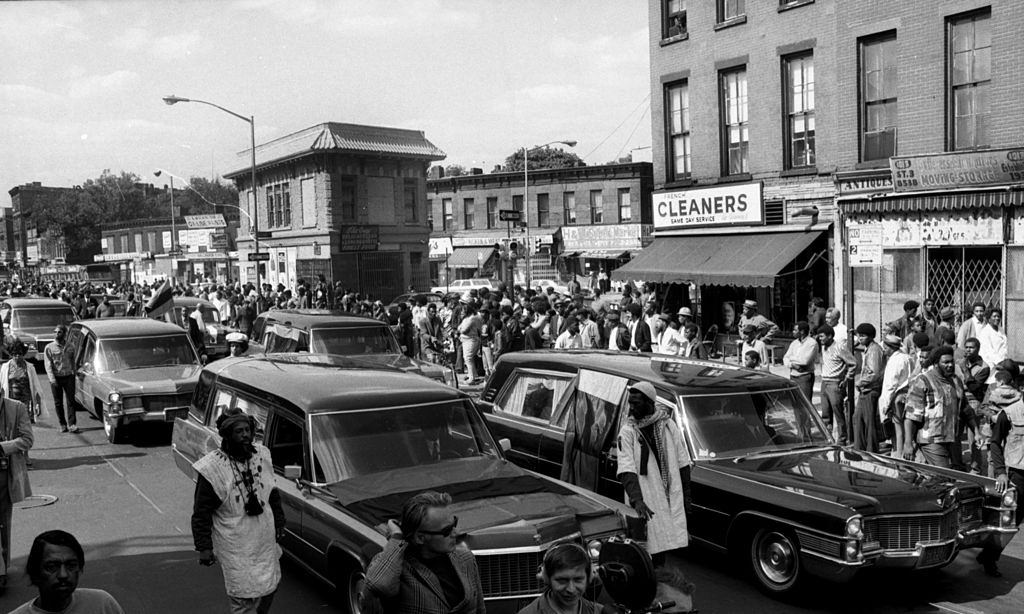 Six hearses carrying Attica dead move slowly in proces sion at Fulton St. and Grand Ave., Brooklyn, 1971.