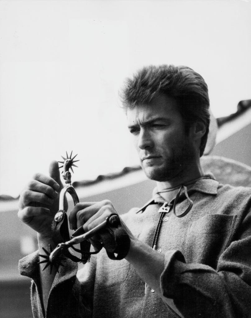 Clint Eastwood inspecting a cowboy boot spur, 1960.