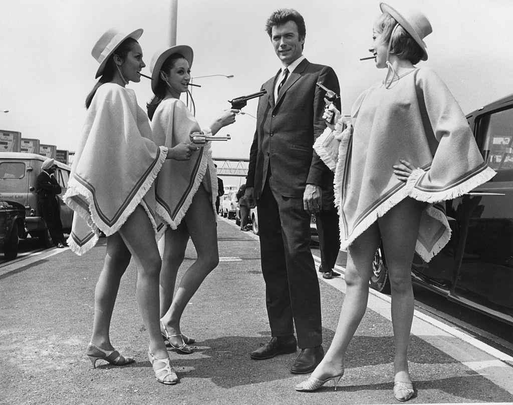 Clint Eastwood with three gun-toting gals upon his arrival at London Airport, 1967.