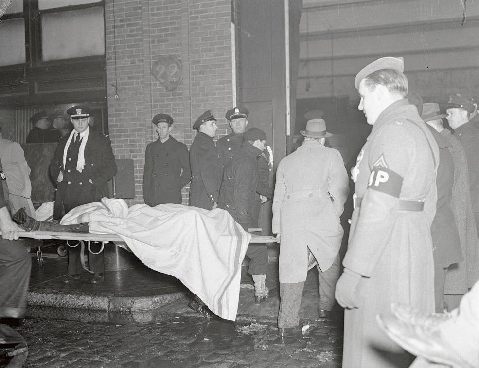 Another victim of the tragic five-alarm fire at the Cocoanut Grove Night Club is carried out on a stretcher from the smouldering ruins.