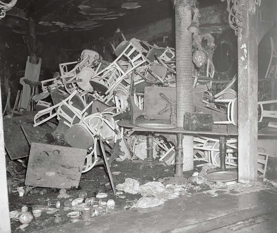 Charred tables and chairs, broken wine glasses and other debris clutter a section of Boston's destroyed Cocoanut Grove Night Club.