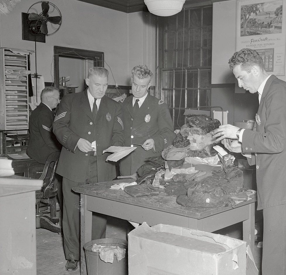 Police examine the pocketbooks of women victims of the Boston fire in an effort to establish the identity of the owners.