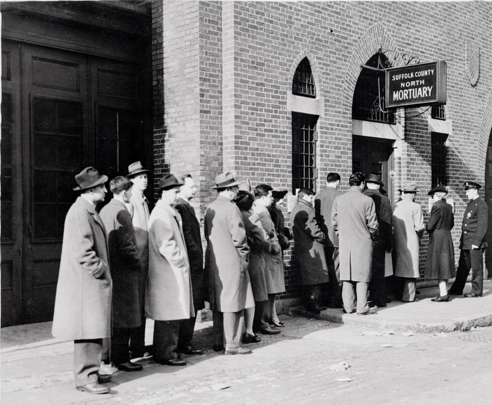 Lined up outside the Suffolk County North Mortuary, stunned relatives wait their turn to be led, two-by-two, before the lines of Cocoanut Grove Night Club fire victims.