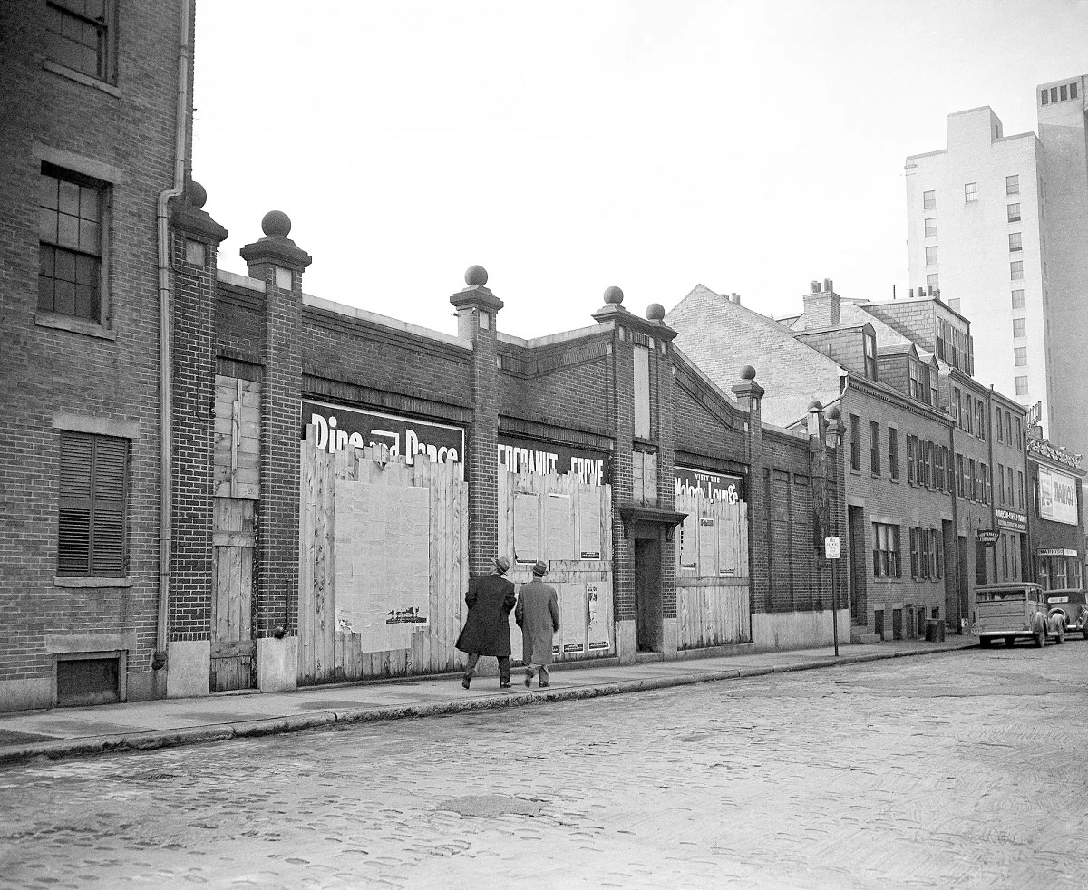 A couple of pedestrians give only a passing glance at boarded up windows of Cocoanut Grove night club in Boston, Nov. 28, 1944.