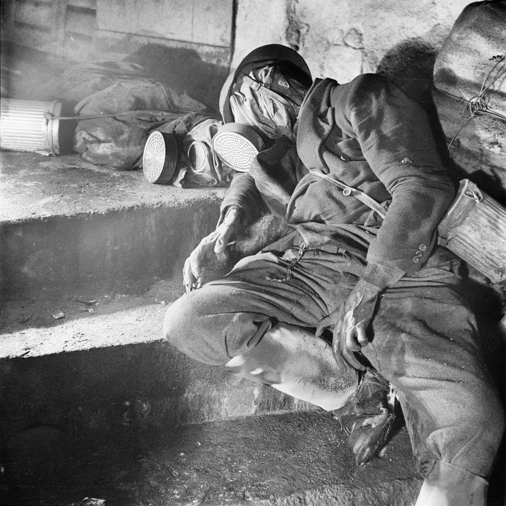 A deceased body with a gas mask and a steel helmet in an air-raid shelter in Dresden