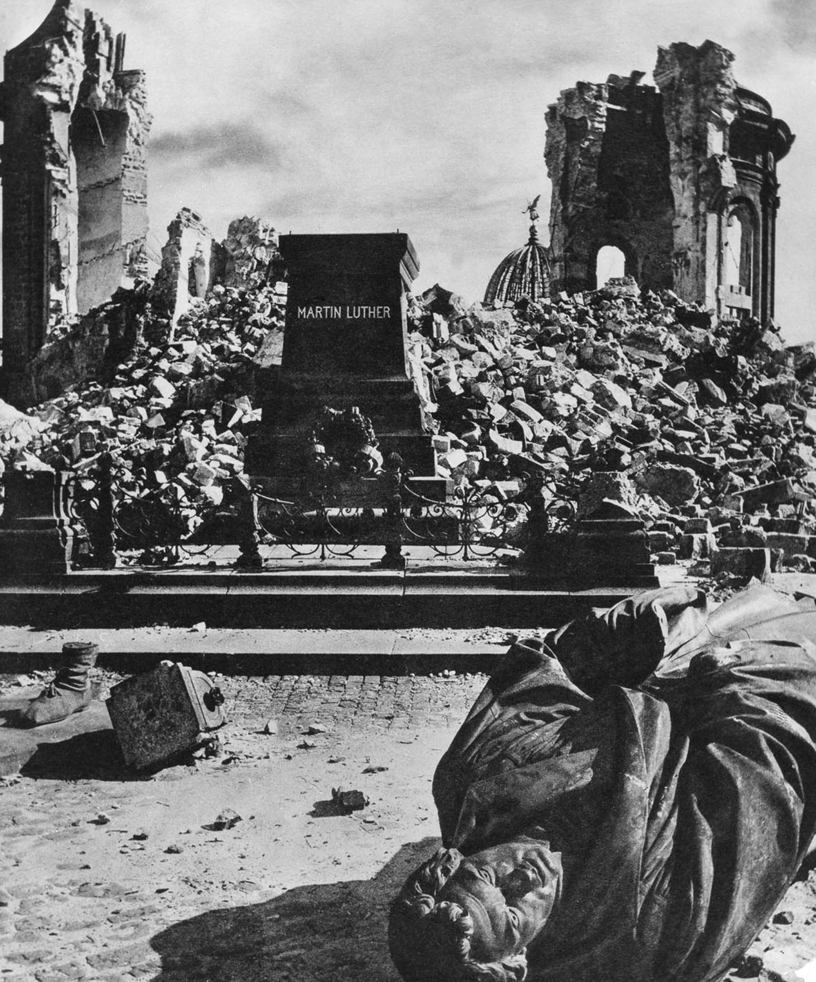 A statue of Martin Luther lies toppled in front of the ruins of the Frauenkirche. 1945.