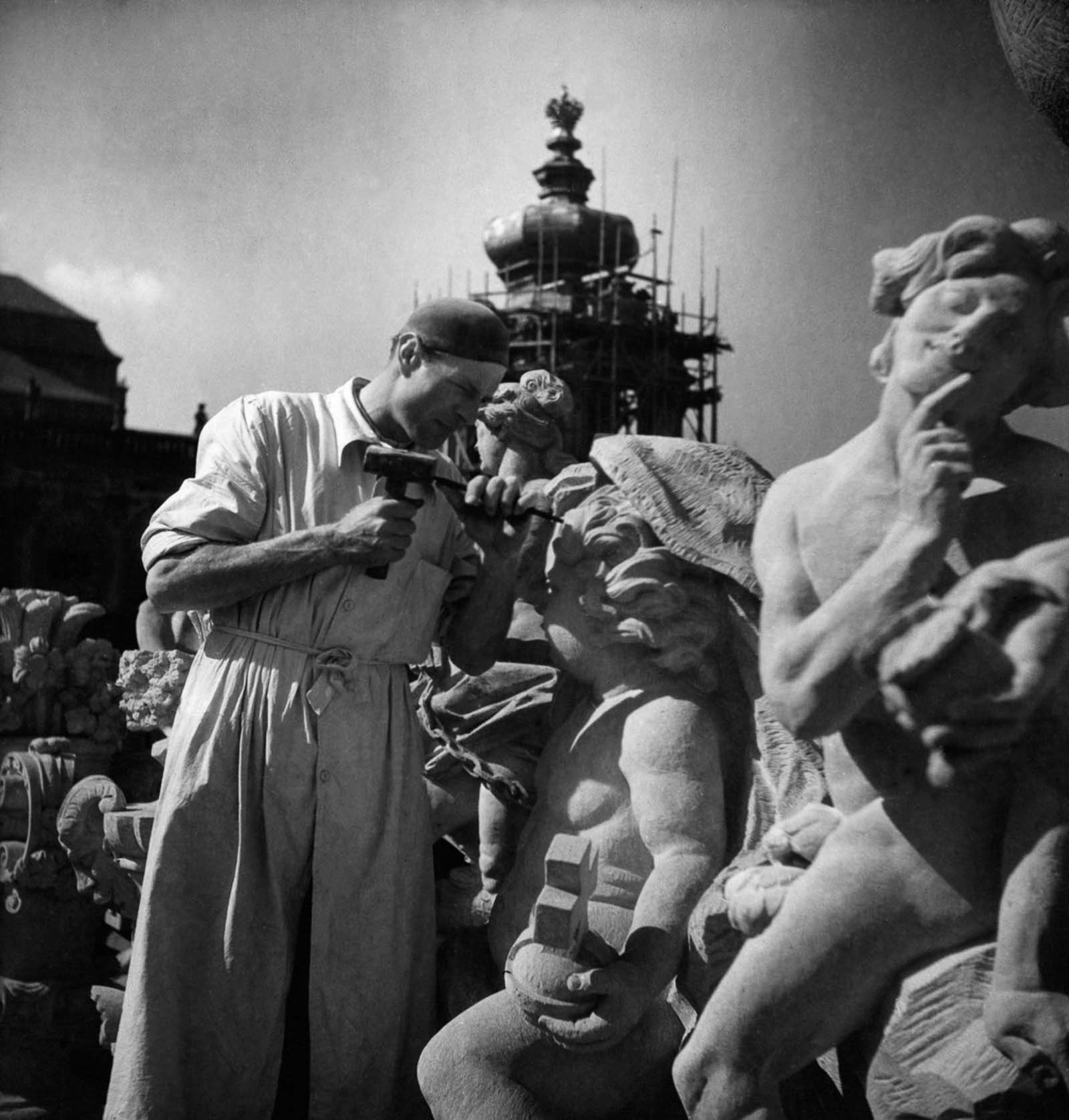 A man makes repairs to a damaged statue, 1949.