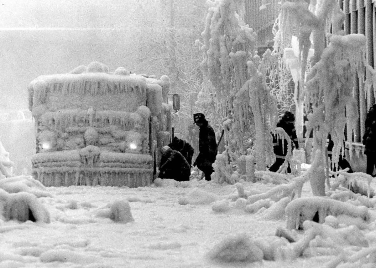 Firemen try to free equipment encrusted in ice after their fight with a five-alarm fire in a vacant hotel in Brooklyn.