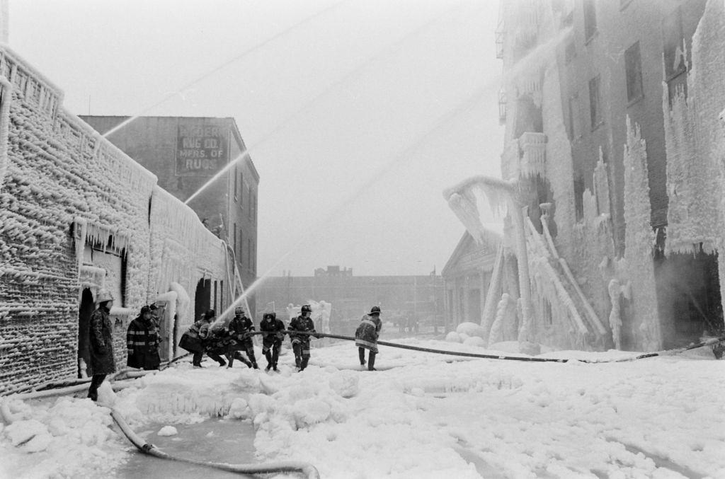 Firemen spraying water on fire building during a snowstorm, United States, 1961