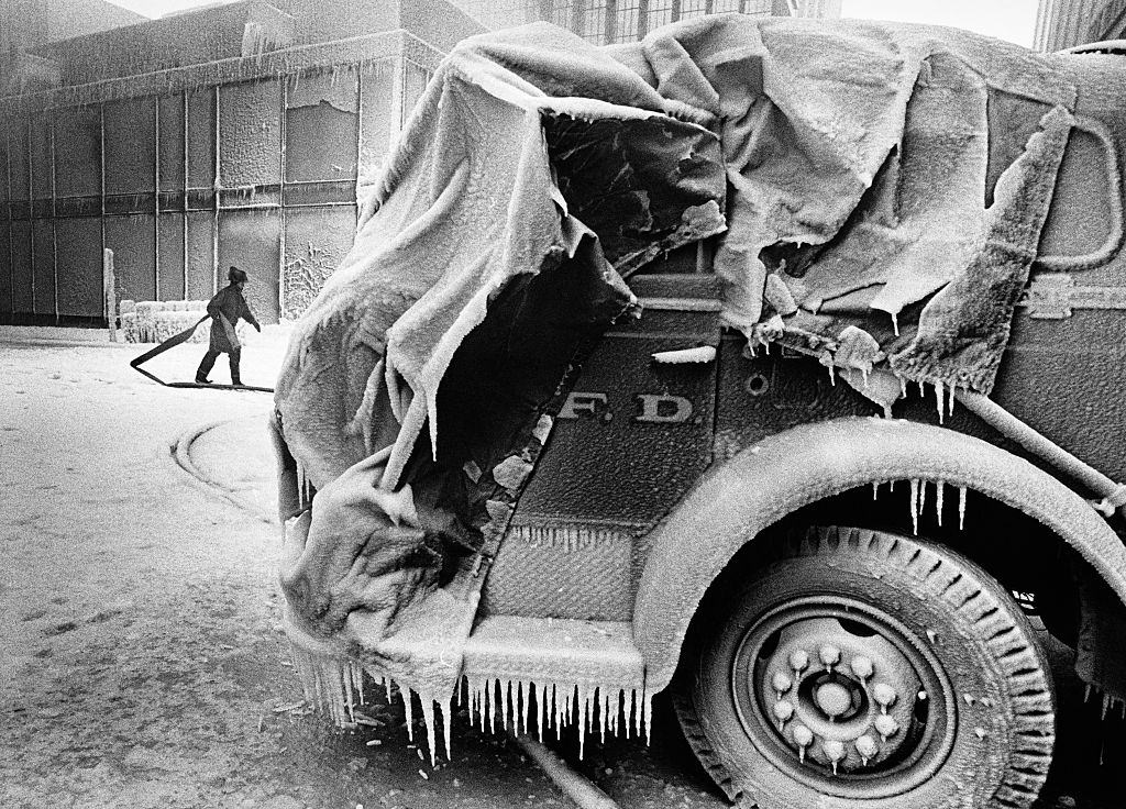 A firefighter carries a hose between an ice-covered fire engine and burning buildings in downtown Minneapolis on Thanksgiving Day, 1982.
