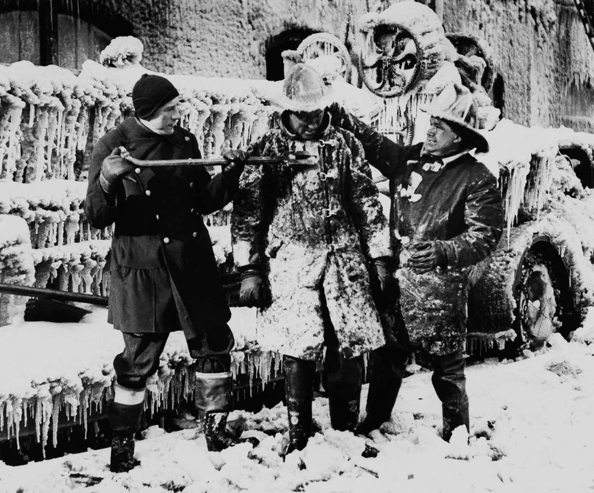 New York firefighters help a colleague chip the ice off his uniform, 1936.