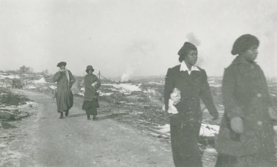 Women from Africville, the black district of Halifax, make their way through the rubble.