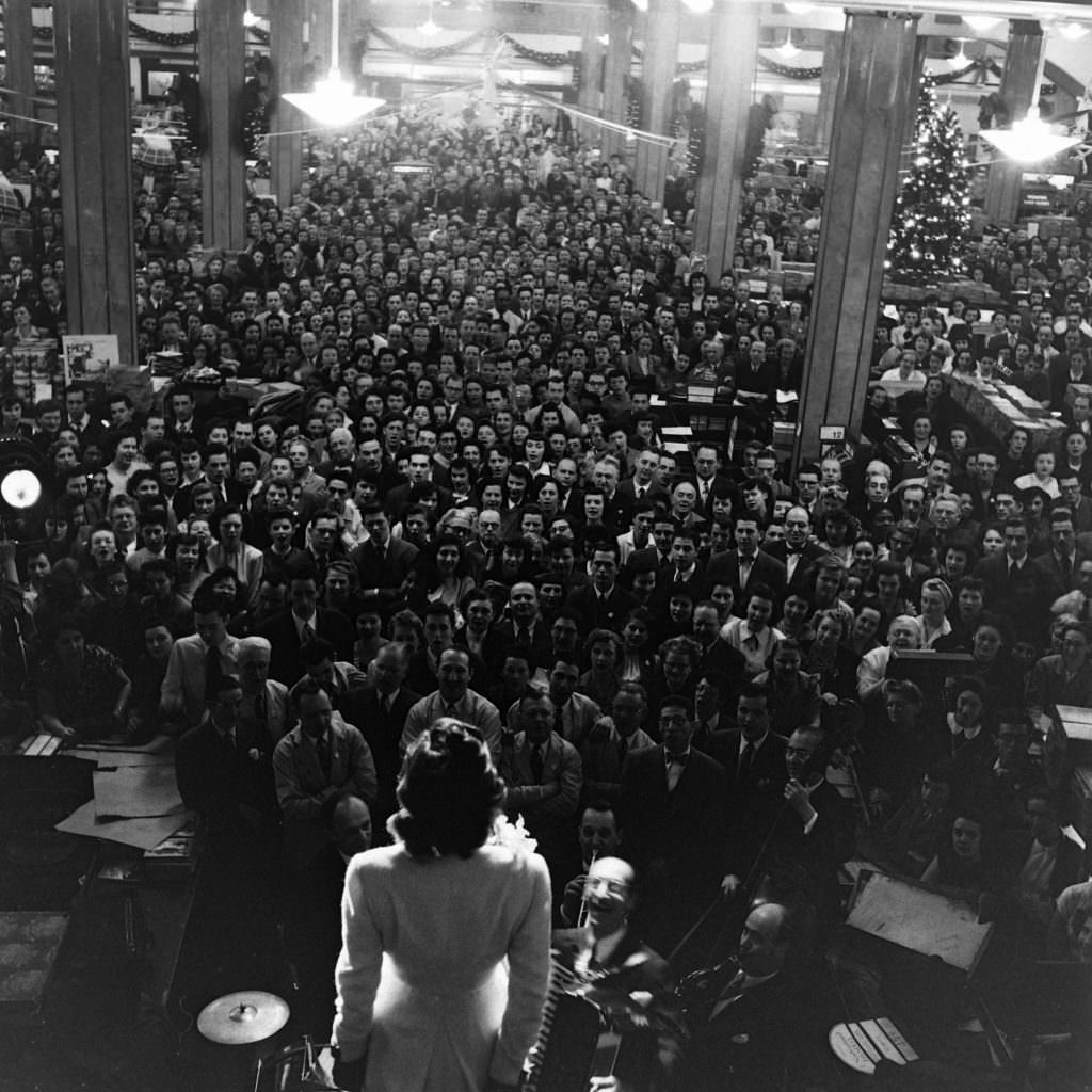 Jane Pickens leads 9,000 Macy’s employees in 'Jingle Bells' during a giant rally designed to whip up the fever of salesmanship for the 1948 Christmas rush.