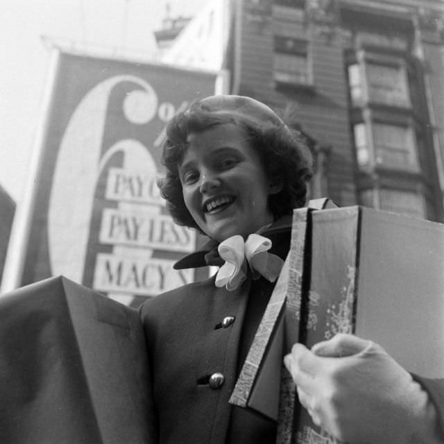 Woman carrying shopping boxes in the course of the Macy's caters to customers.