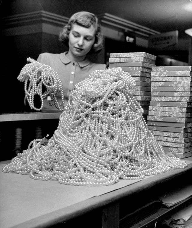 An employee plowing through a pile of costume pearl necklaces that she will sell.
