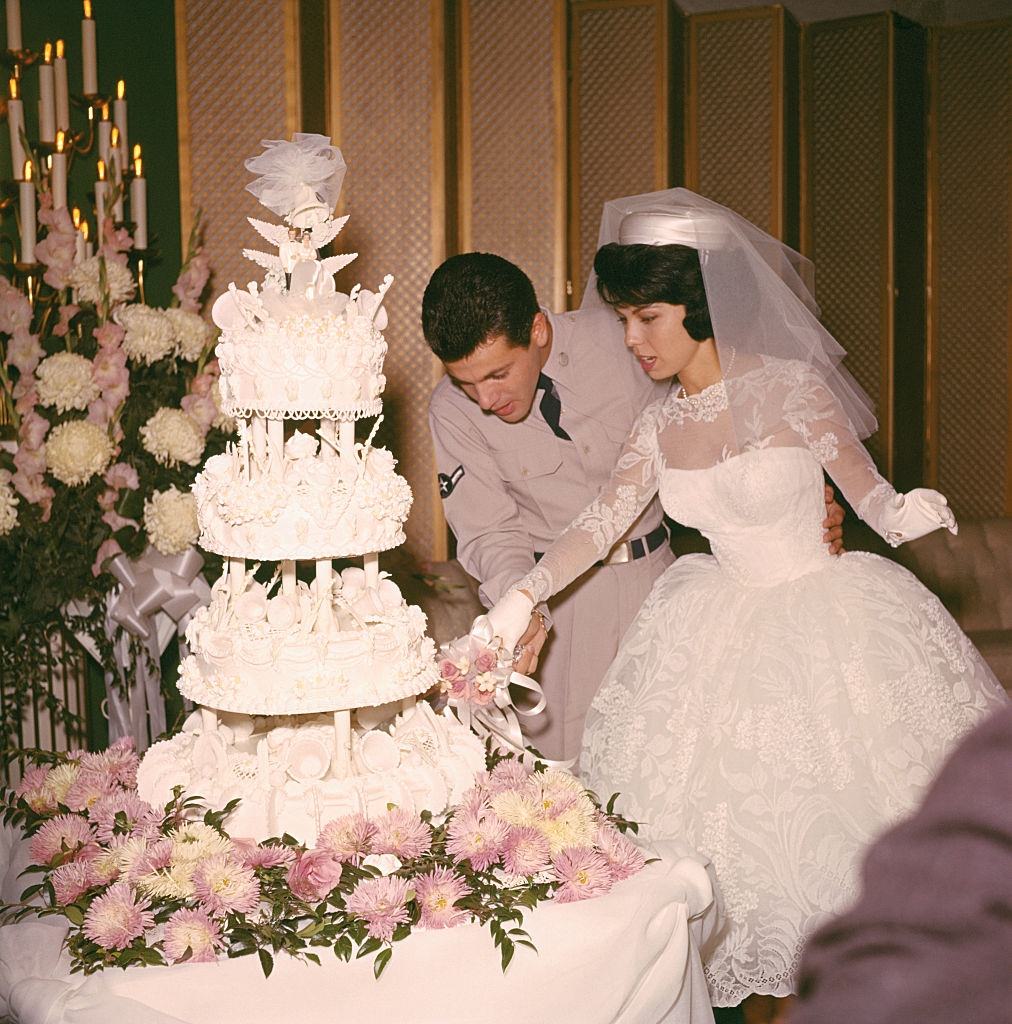 Nancy Sinatra and Tommy Sands are shown together as they cut their wedding cake.
