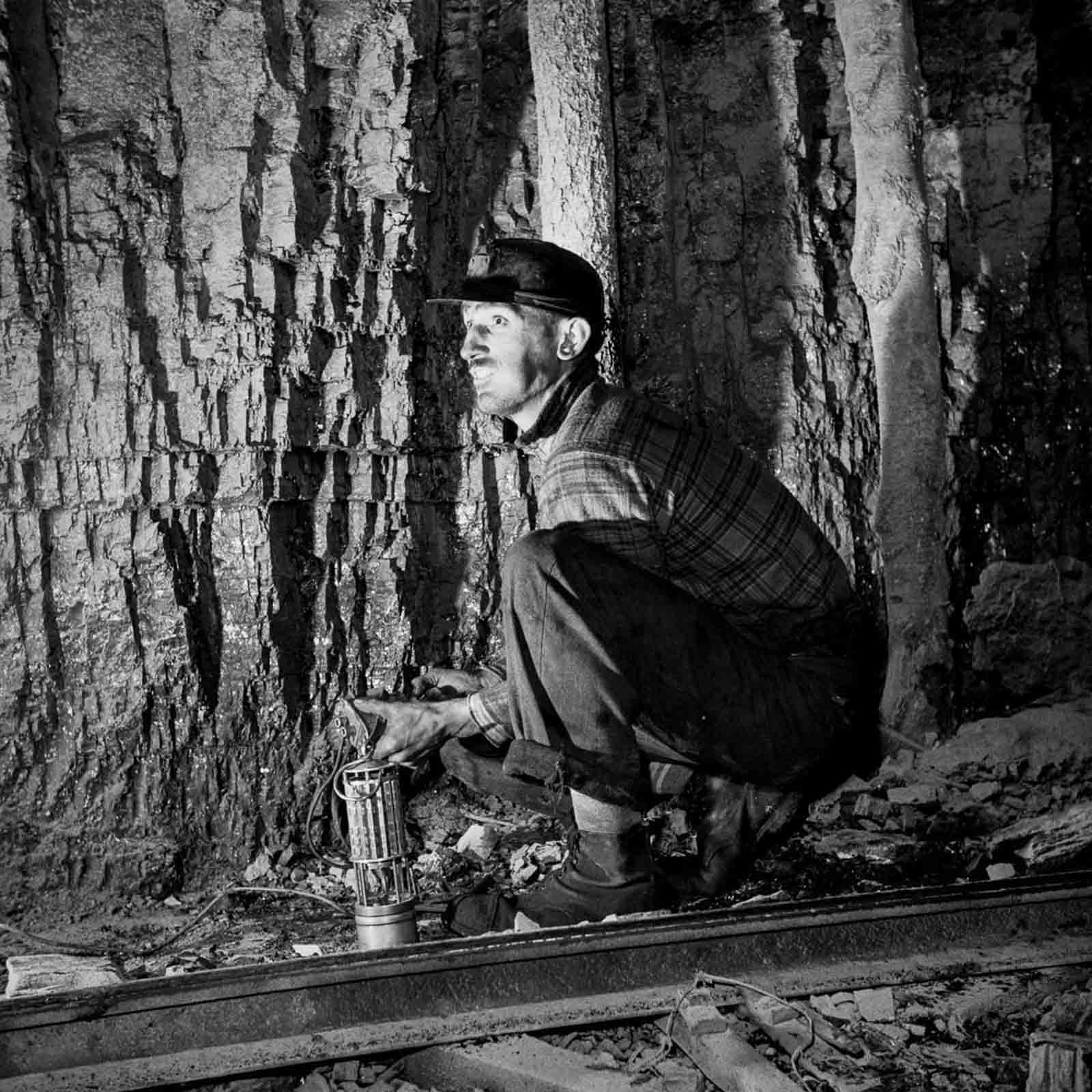 A miner detonates a stick of dynamite.