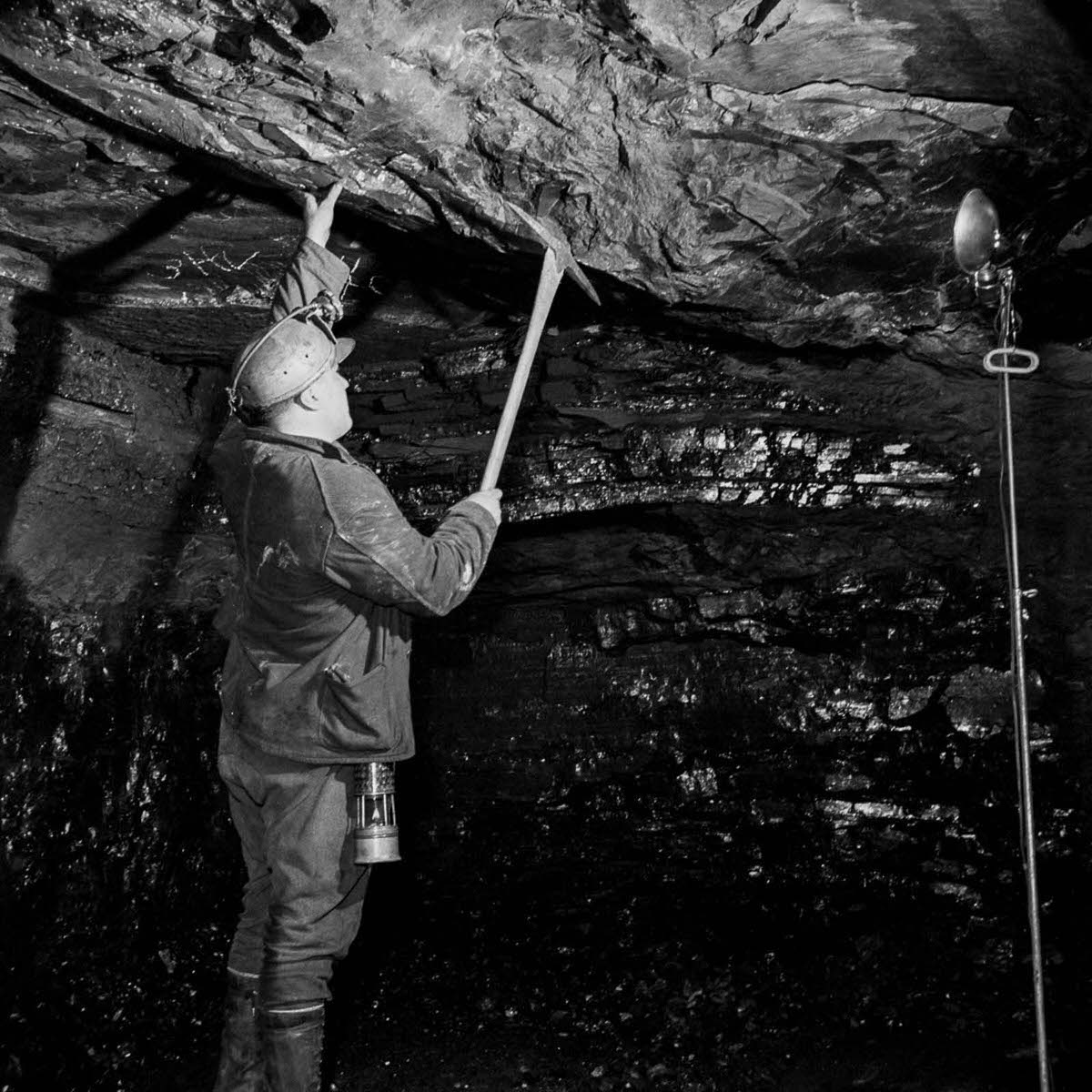 A miner tests the stability of the tunnel roof.