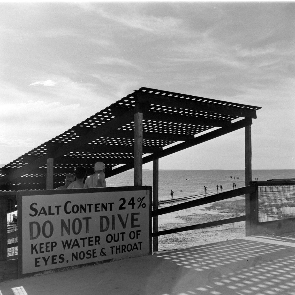Sign that says 'Salt Content 24% Do Not Dive Keep Water Out Of Eyes, Nose And Throat' at the Great Salt Lake, Salt Lake City, June 1948.