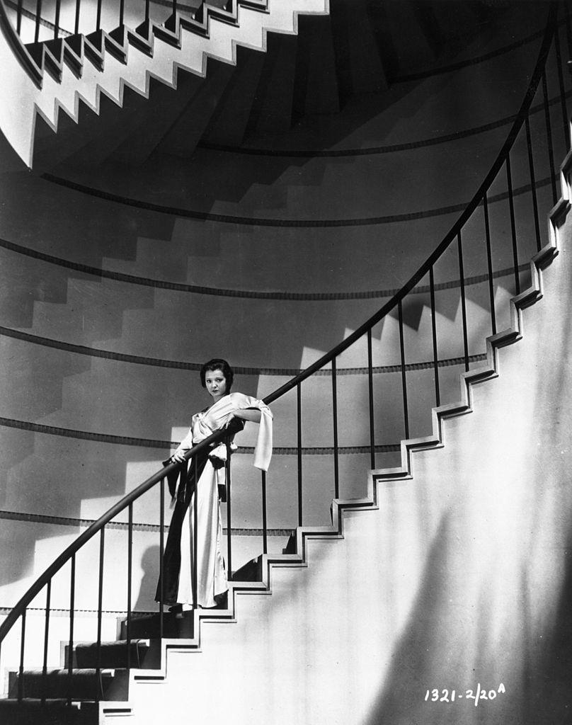 Sylvia Sidney standing on a spiral staircase, 1935.