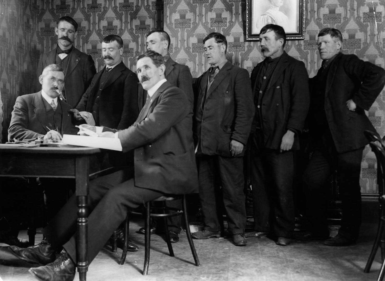 J. Hanson, seated right, district secretary of the National Sailors and Firemen’s Union, awards shipwreck pay to survivors.