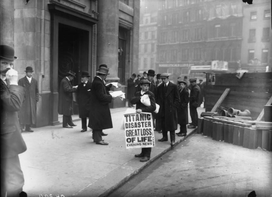 A newspaper boy sells copies of the Evening News telling of the Titanic sinking outside the off ice of the White Star Line