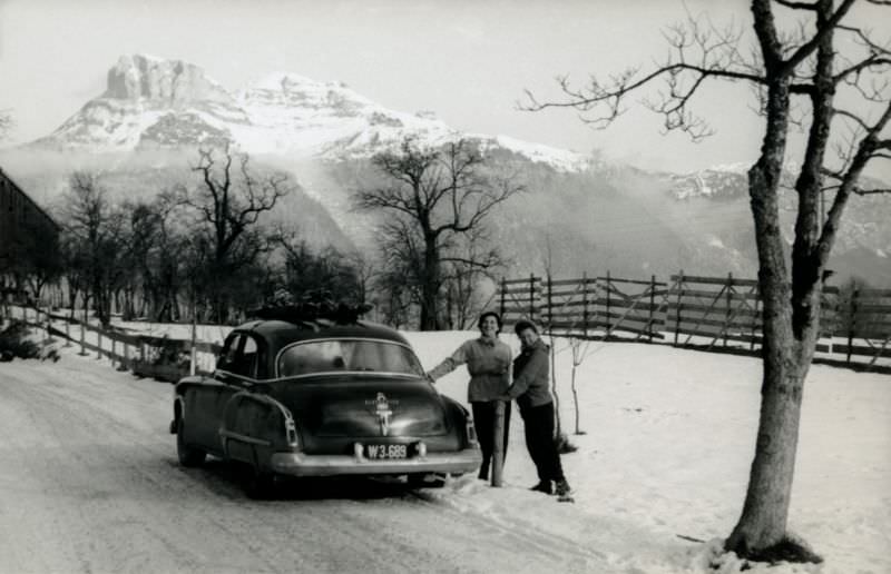 Two cheerful ladies posing with a 1949 Oldsmobile 4-Door Sedan on a snow-covered road in the countryside.