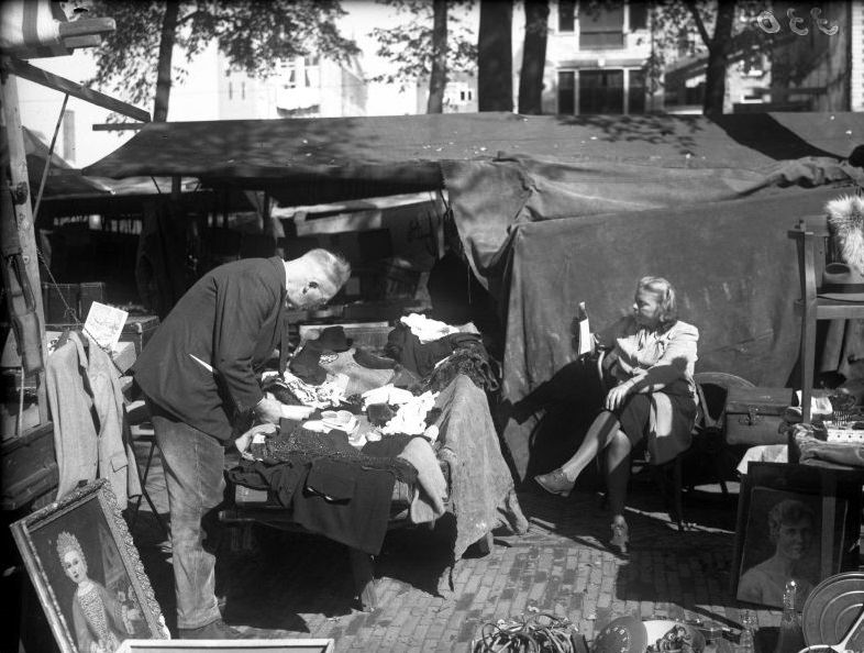 Market on the Waterlooplein, woman reads newspaper behind her stall. Amsterdam, September 1946