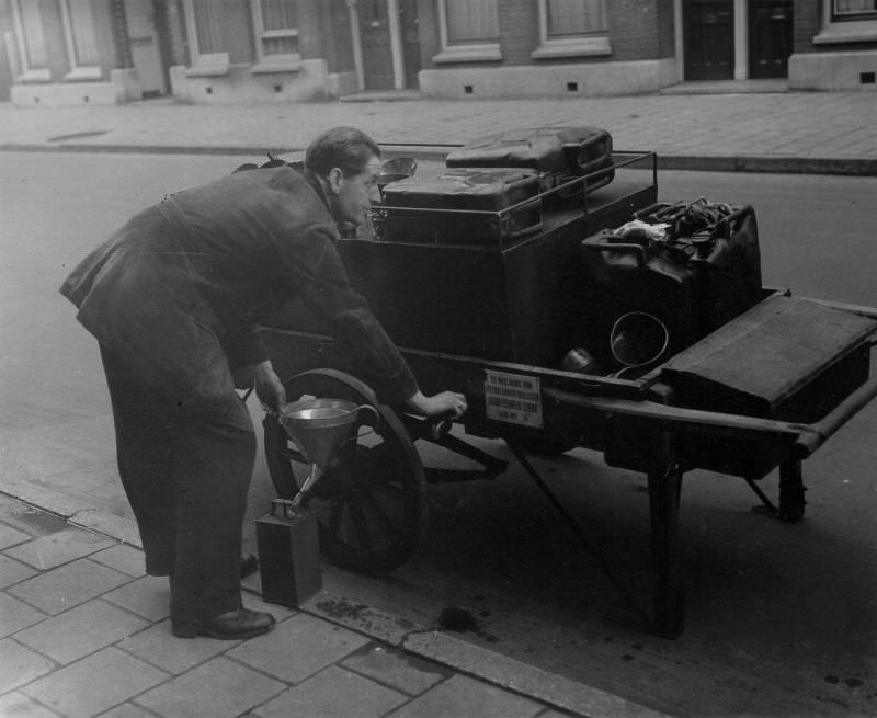 Member no. 5 of the Dutch Association of Petroleum Dieticians 'By Unity Strong' fills an oil can on the street. Amsterdam, January 14, 1948