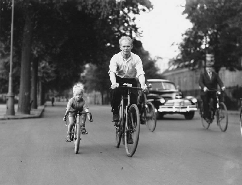 Little boy riding a mini-road bike under the guidance of his father, Sarphatistraat. Amsterdam, July 13, 1949