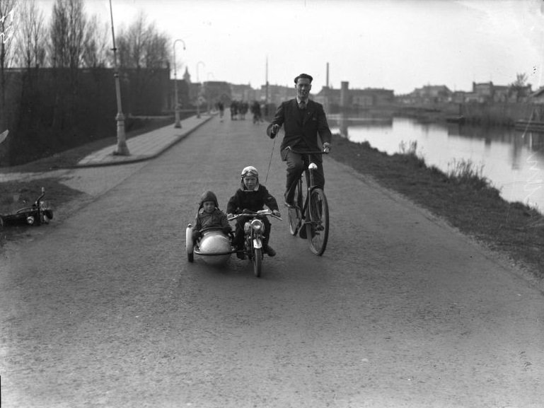 Children on miniature motorcycle with sidecar under the guidance of their father, 1946