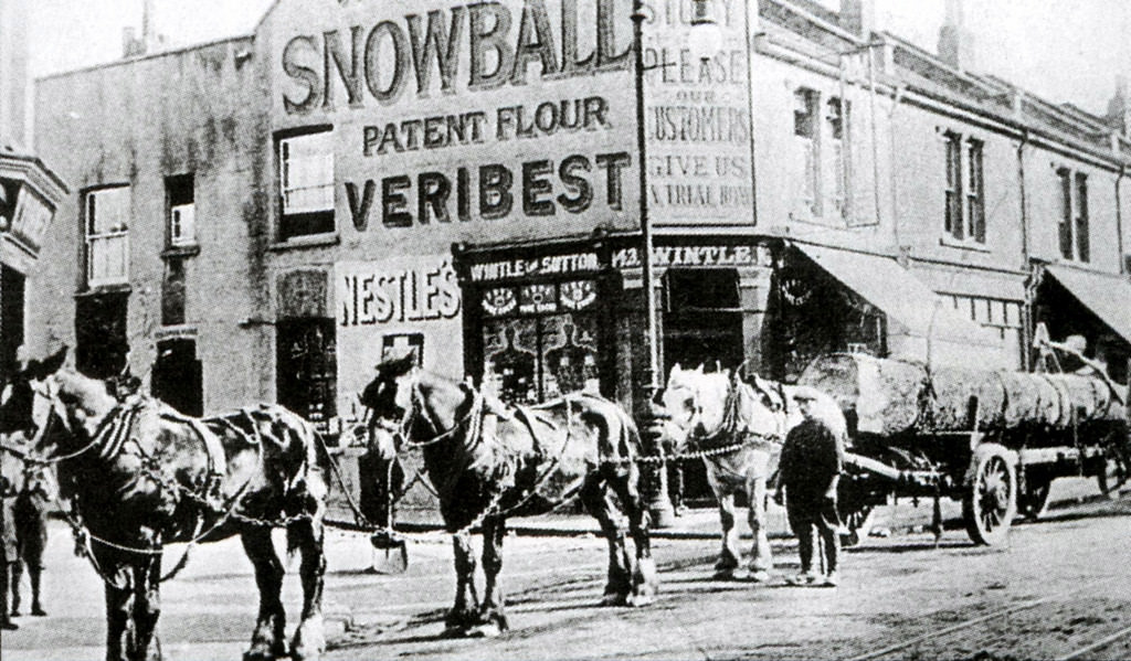 A loaded timber carriage pulled by three horses waiting to unload at Toogood’s timber yard, West Street, Bedminster, 1899