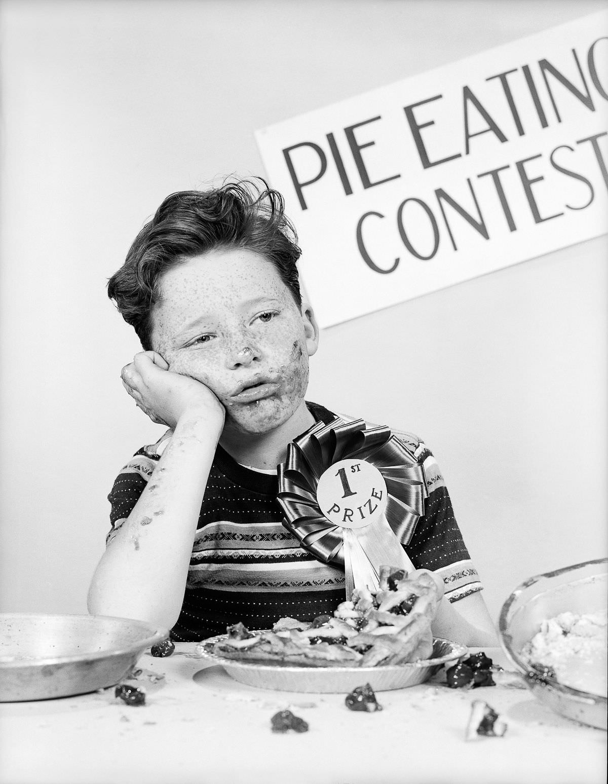 A six-year-old boy is pictured with food all over his face, as he recovers after eating a 10 inch cranberry pie in just fifteen seconds, 1948.