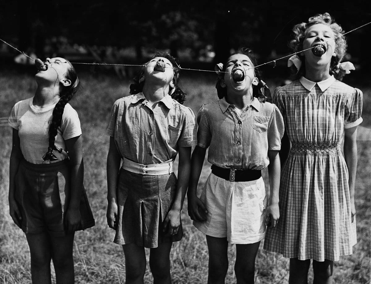 London students attempt to eat potatoes hung on a line, 1952.