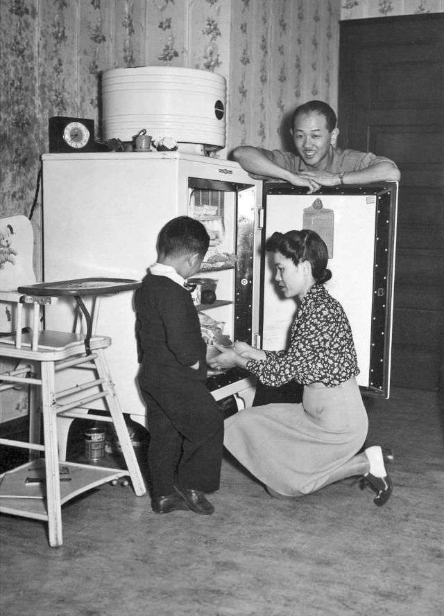The honored American custom of raiding the icebox is especially pleasurable to the Yamadas after life in a relocation center, Peoria, Illinois, 1944.