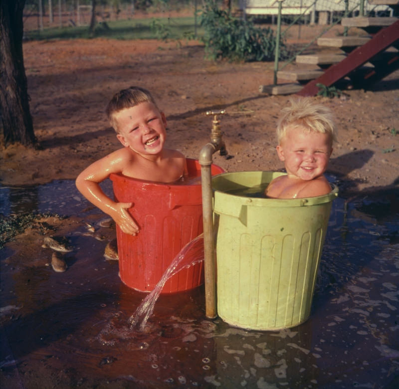 Children cooling off next to house, October 1961