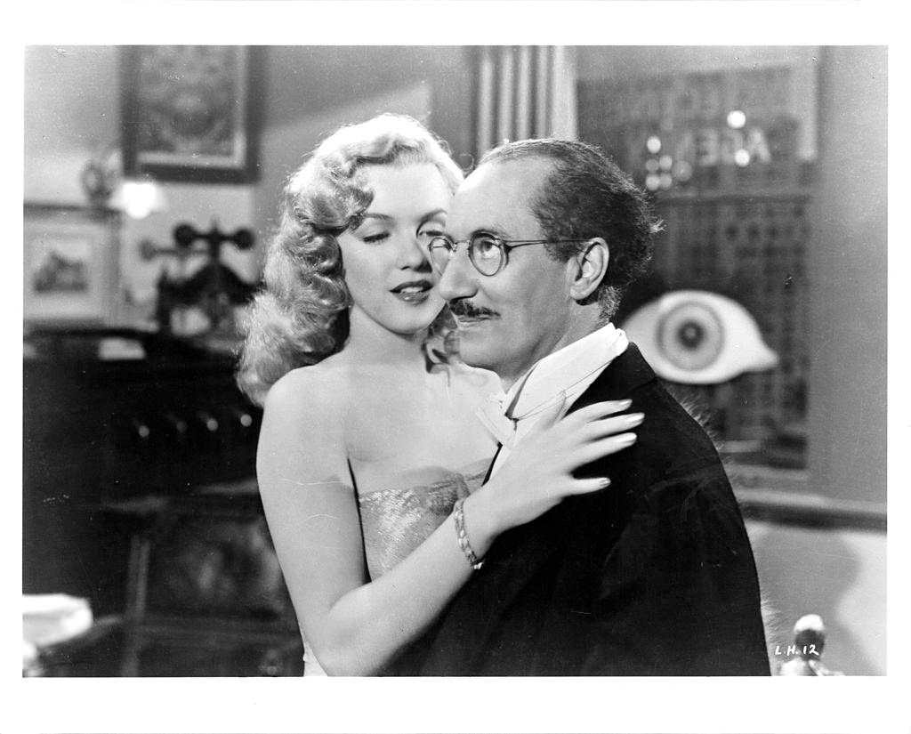 Marilyn Monroe embraces Groucho Marx in a scene from the film 'Love Happy', 1949.