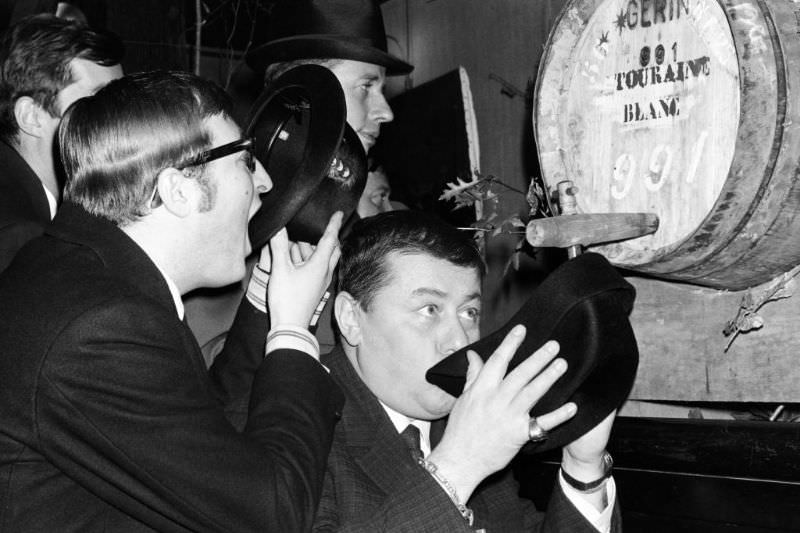 Two men drinking wine from a barrel in Paris.