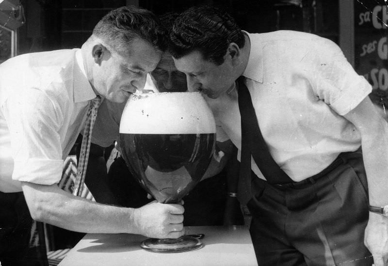 Three men drinking from a large glass of beer.