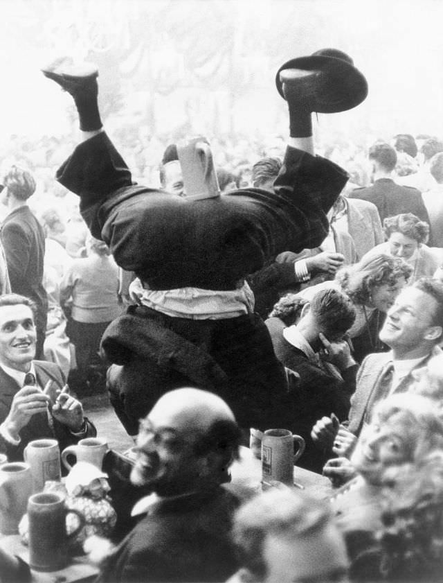 A man doing headstand in a beer tent at the Oktoberfest.