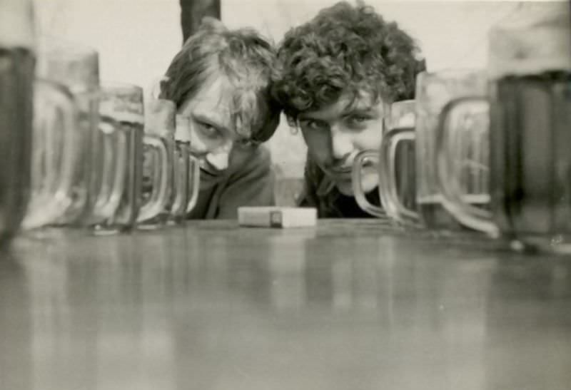 A pair of young men with glasses of beer.