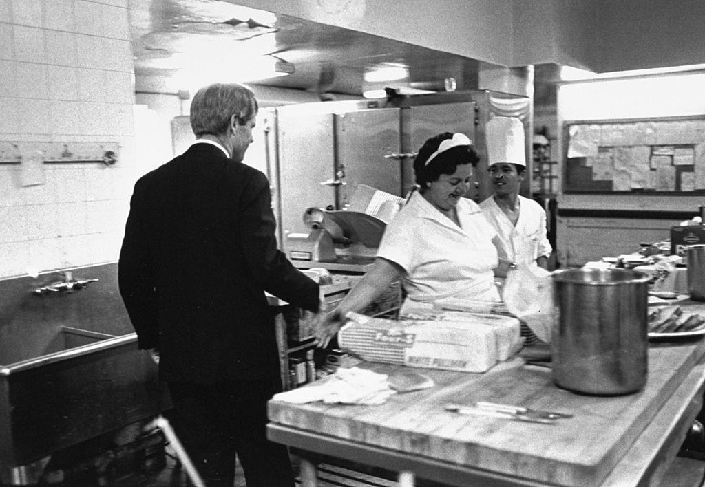 Robert Kennedy shaking hands w. kitchen help en route to podium in ballroom to deliver his victory speech at the Ambassador Hotel prior to his assassination.