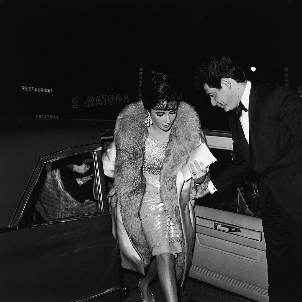 Elizabeth Taylor steps from a car, escorted by her husband Eddie Fisher as they arrive at the premiere of the film, 'Suddenly Last Summer,' 1959.
