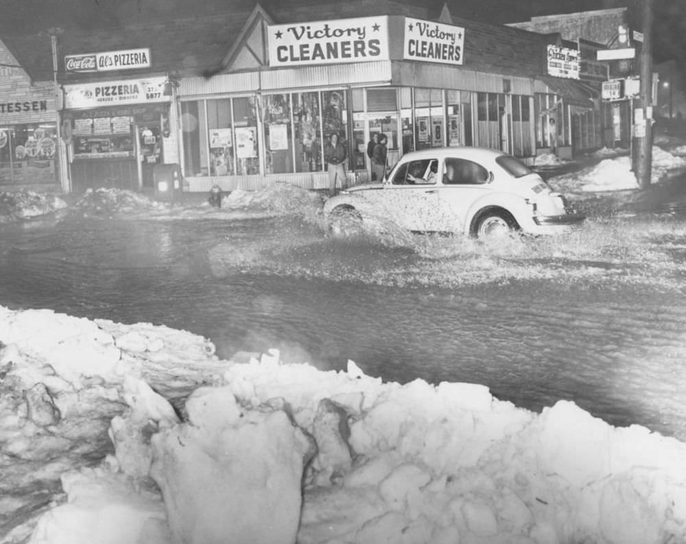 A Volkswagen "bug" splashes through the water at Victory Blvd. and Jewett Ave.