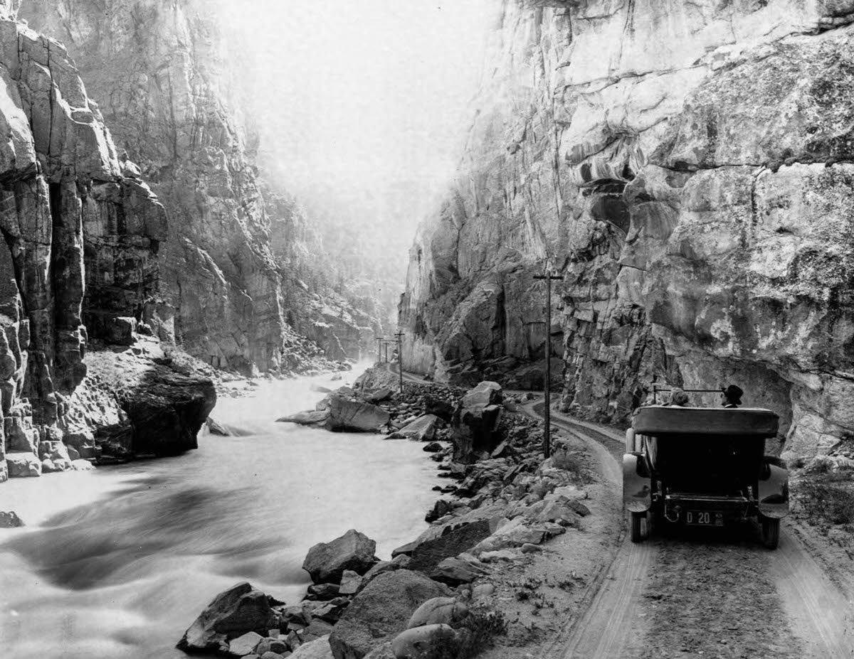 Tourists drive their car on a dirt road along the Yellowstone River, 1899.