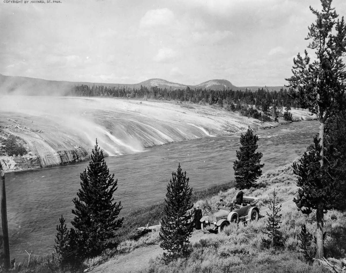 Tourists watch the scalding water from the Excelsior Geyser flow into the Firehole River in Yellowstone, 1917.