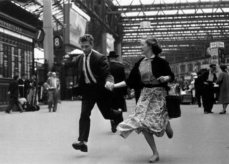 A pair of young employees running through Waterloo train station, London, 1955.