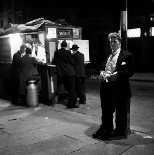 A gang member lounging outside a coffee stall, London, 1953.